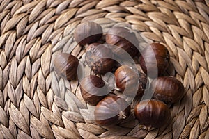 Organic chestnuts on a wicker woven cloth, macro photo.