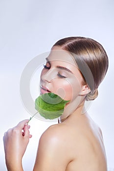 Organic cosmetic . Beautiful woman face portrait with green leaf , concept for skin care or organic cosmetics