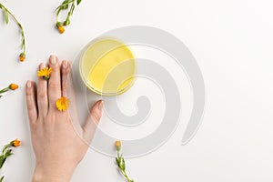 Organic cosmetic concept. Flowers of calendula, female hand and cosmetic cream isolated, on white background