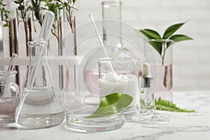 Organic cosmetic products, natural ingredients and laboratory glassware on white marble table