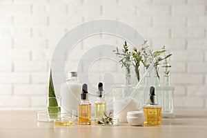 Organic cosmetic products, natural ingredients and laboratory glassware on wooden table