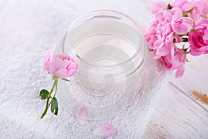 Organic cosmetic with rose and pot of moisturizing face cream on white background top view