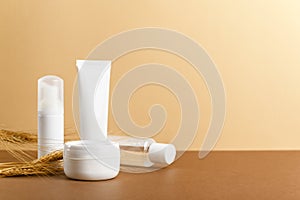 Organic cosmetic white packages with wheat ears composition. Natural skincare products unbranded plastic bottles on beige