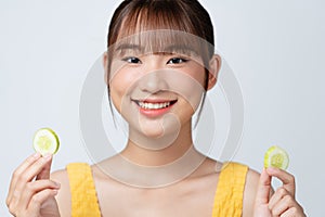 Organic cosmetics concept. A young girl with clean skin holds cucumber slices near her face