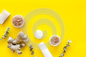 Organic cosmetics with ginger and herbs on yellow background top view mockup