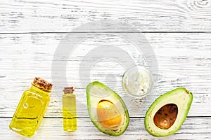 Organic cosmetics with natural ingredients. Avocado essential oil near half of avocado on white wooden background top