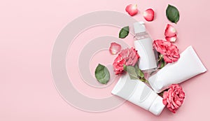 Organic cosmetics with a rose flower and green leaves on a pink background. Copy space, flat lay