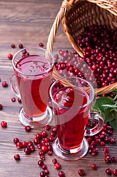 Organic cranberry juice in glasses with berries on wooden background