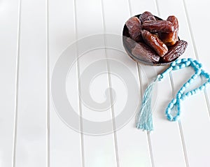 Organic dates Medjool in wooden coconut bowl and rosary.