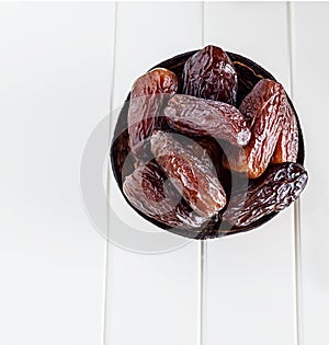 Organic Dates Medjul in coconut bowl on white background. Ramadan concept