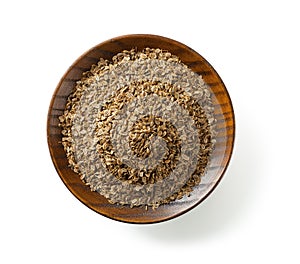 Organic dill seeds on a wooden saucer isolated on a white background. Cutout of whole anethum graveolens fruits on a plate.