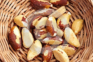 Organic dried Brazil nuts in rustic rattan bowl close up. Tasty nutty snack