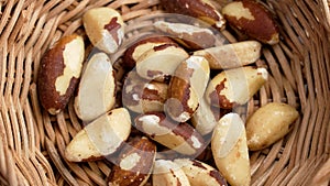 Organic dried Brazil nuts in rustic rattan bowl close up. Tasty nutty snack.
