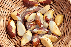 Organic dried Brazil nuts in rustic rattan bowl close up. Tasty nutty snack photo