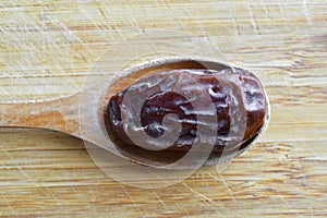 Organic dried hurma dates medjool grains, in wooden spoon on cutting board