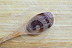 Organic dried hurma dates medjool grains, in wooden spoon on cutting board