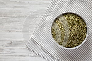 Organic Dried Rosemary in a Bowl on a white wooden background, top view. Flat lay, overhead, from above