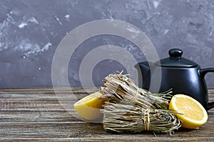 Organic dry lemongrass Cymbopogon flexuosus in bunches and lemon fruit on a wooden table.