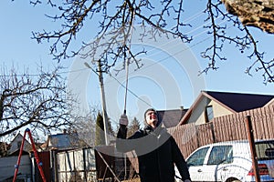 Organic ecological agriculture. Defocus farmer man spraying tree with manual pesticide sprayer against insects in spring garden.