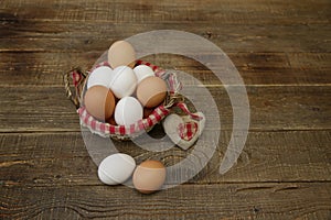 Organic eggs in a basket with a decorated checkered napkin and a heart made of linen fabric on a wooden rustic background