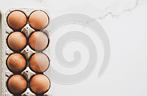 organic eggs in egg box on white marble kitchen table