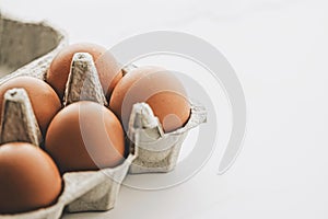 organic eggs in egg box on white marble kitchen table