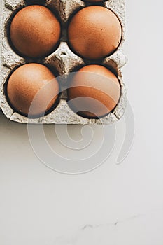 organic eggs in egg box on white marble kitchen table