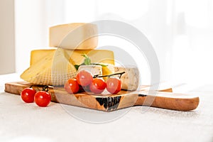 Organic farm products: home-made goat cheese cheeses lie on a wooden board on a light background