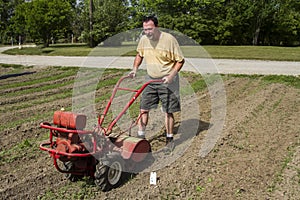 Organic Farmer Cultivating Between Rows In A Hot Sun