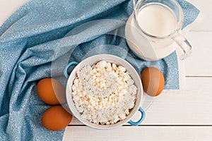 Organic farming cottage cheese in a blue bowl, eggs and milk