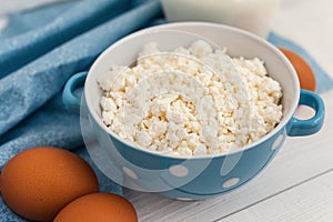 Organic farming cottage cheese in a blue bowl, eggs and milk