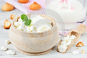 Organic farming cottage cheese in a wooden bowl on a white table