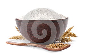 Organic flour in bowl, spoon with grains of wheat and spikelets on background