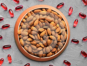 Organic food and chemical medicines, biologically active food supplement, almonds and chemical vitamins on gray background, top