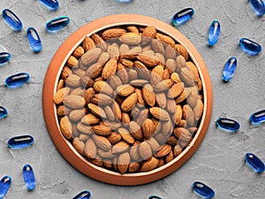 Organic food and chemical medicines, biologically active food supplement, almonds and chemical vitamins on gray background, top