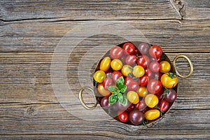 Organic food. Colorful Cherry tomatoes in rustic colander on old wooden table. Top view,