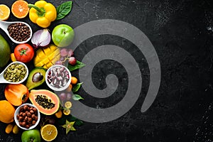 Organic food. Fruits, vegetables, beans and nuts on a black stone background. Top view.