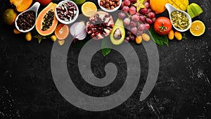 Organic food. Fruits, vegetables, beans and nuts on a black stone background. Top view.