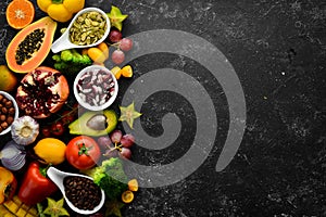 Organic food. Fruits, vegetables, beans and nuts on a black stone background. Top view.