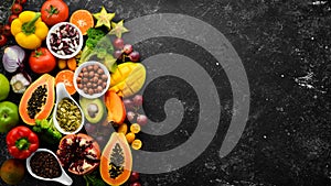 Organic food. Fruits, vegetables, beans and nuts on a black stone background. Top view.