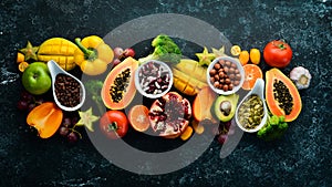 Organic food. Fruits, vegetables, beans and nuts on a black stone background. Top view.