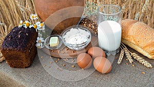 Organic food - milk, bread, eggs, cheese, butter lying on the table, against the background of a wheat field.