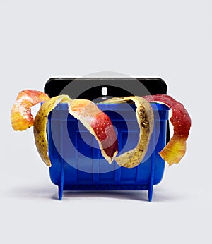 Organic food waste concept, potato and apple peeling at plastic blue toy trash garbage can bin