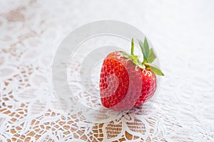 Organic fresh farm strawberries close up lying on a Lacy white tablecloth.