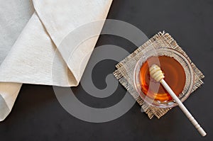 Organic fresh liquid honey in glass bowl with dipper on rustic background