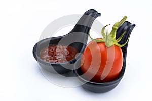 Organic and fresh red tomato with catchup in ceramic spoons on white background