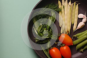 Organic fresh vegetables courgette, tomato, asparagus, basil, dill, green peas, garlic in a frying pan