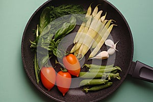 Organic fresh vegetables courgette, tomato, asparagus, basil, dill, green peas, garlic in a frying pan