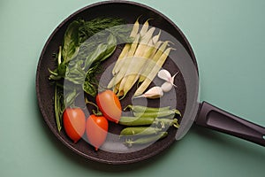 Organic fresh vegetables courgette, tomato, asparagus, basil, dill, green peas, garlic in a frying pan