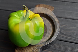 Organic green pepper in wooden plate on dark wooden table background, top view, copy space